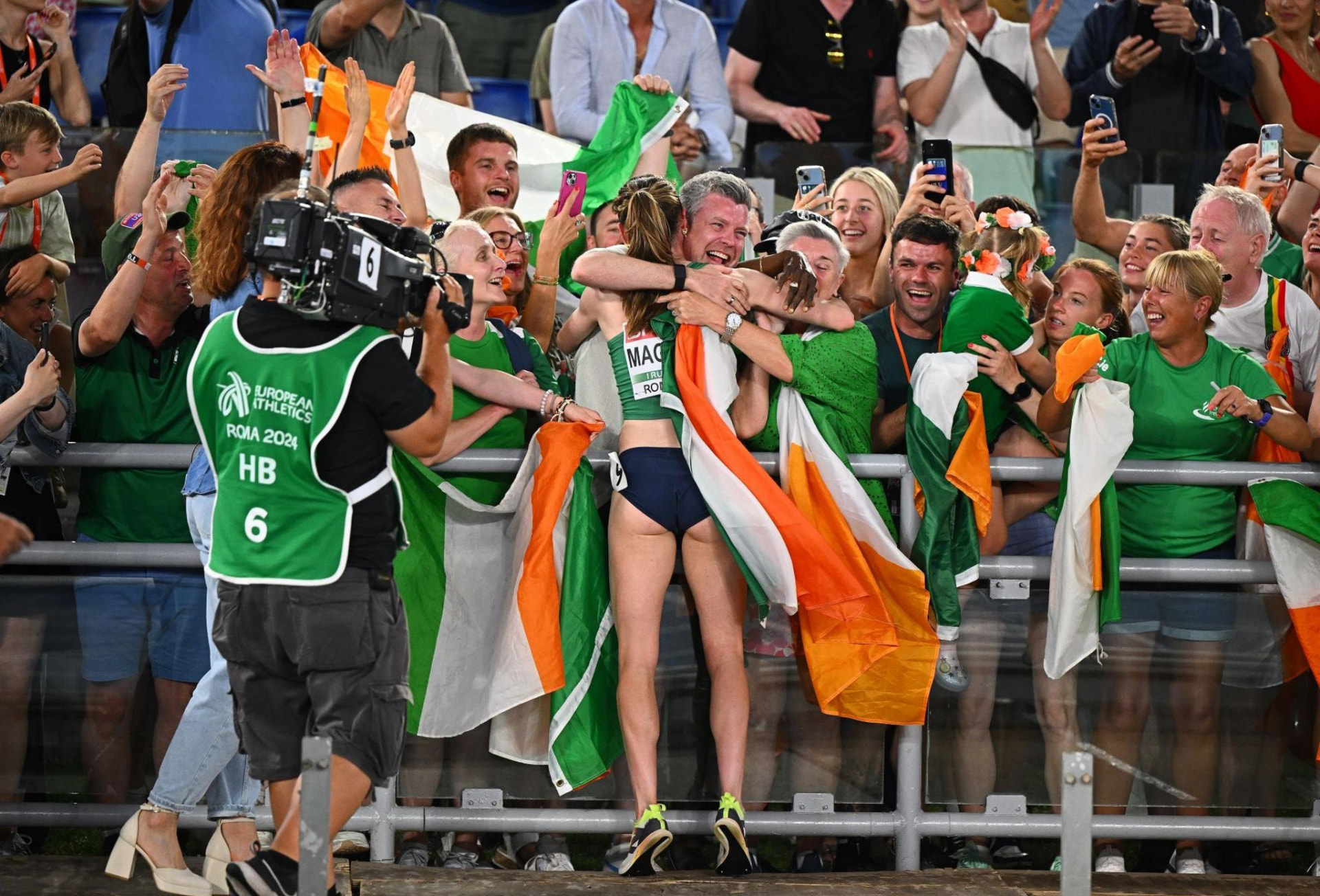 Irish athletics fans celebrate with an athlete wrapped in the tricolour at a championship